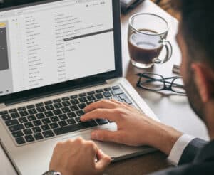 Ein Mann sitzt am Laptop und verschickt E-Mails