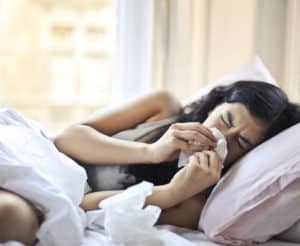 frau-liegt-mit-schnupfen-im-bett-und-schnaubt-sich-die-nase